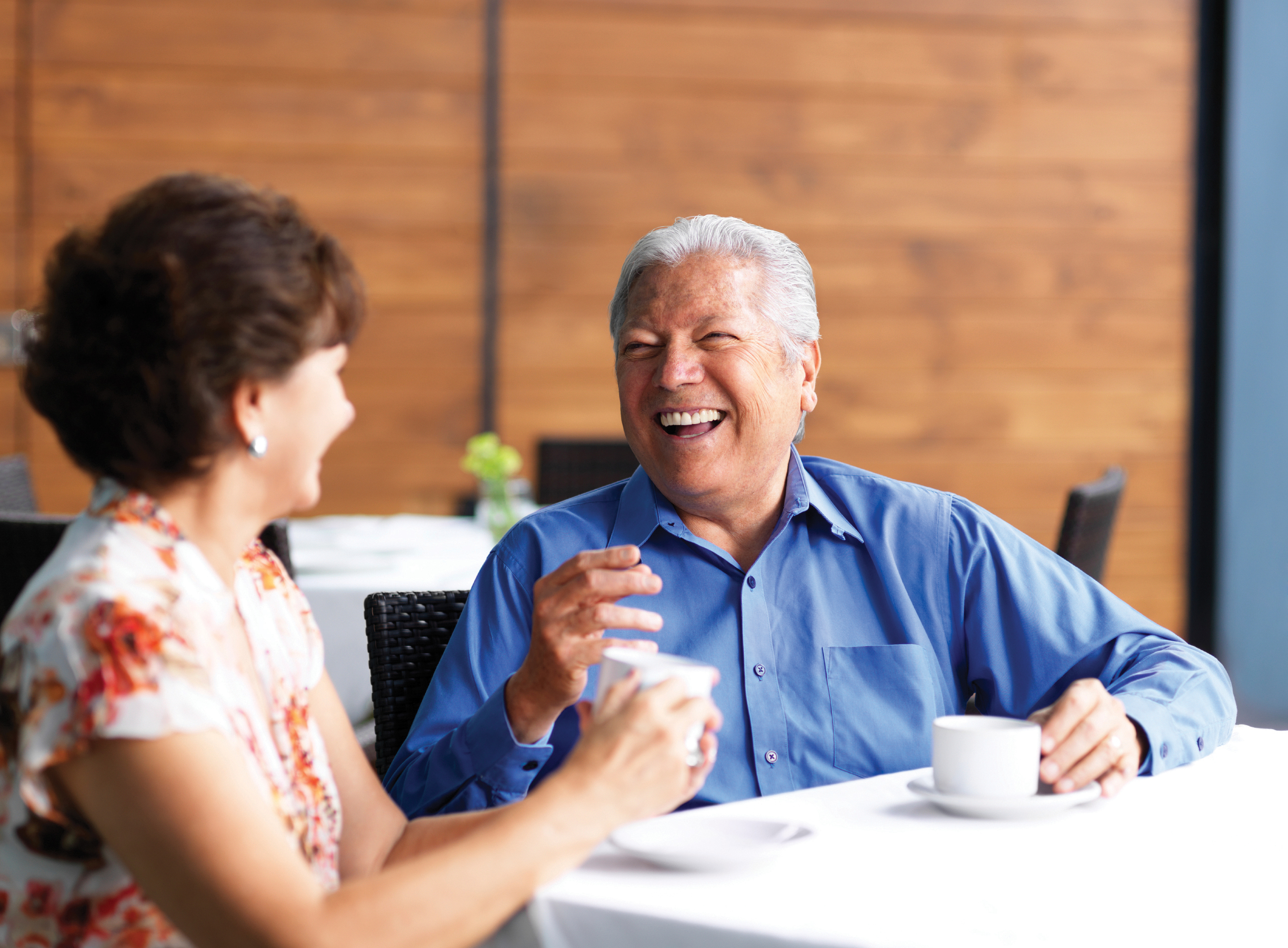 A senior couple laughs over a cup of coffee.